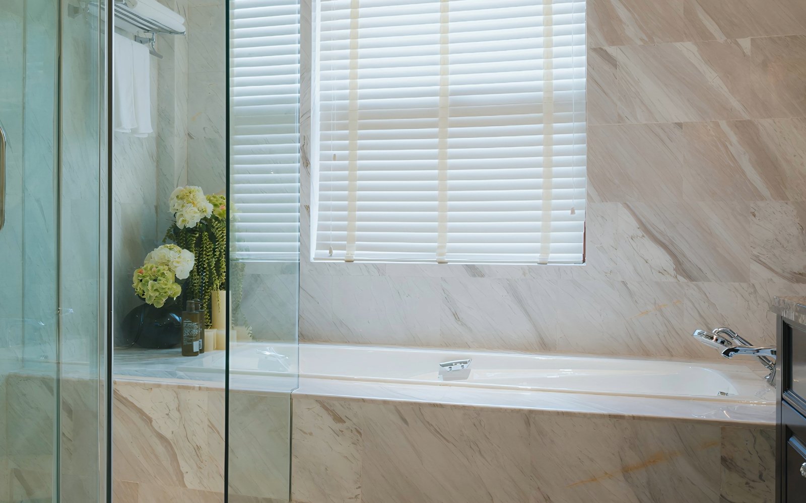Neutral marble bathroom remodel in Los Angeles with marble tub and shower surround